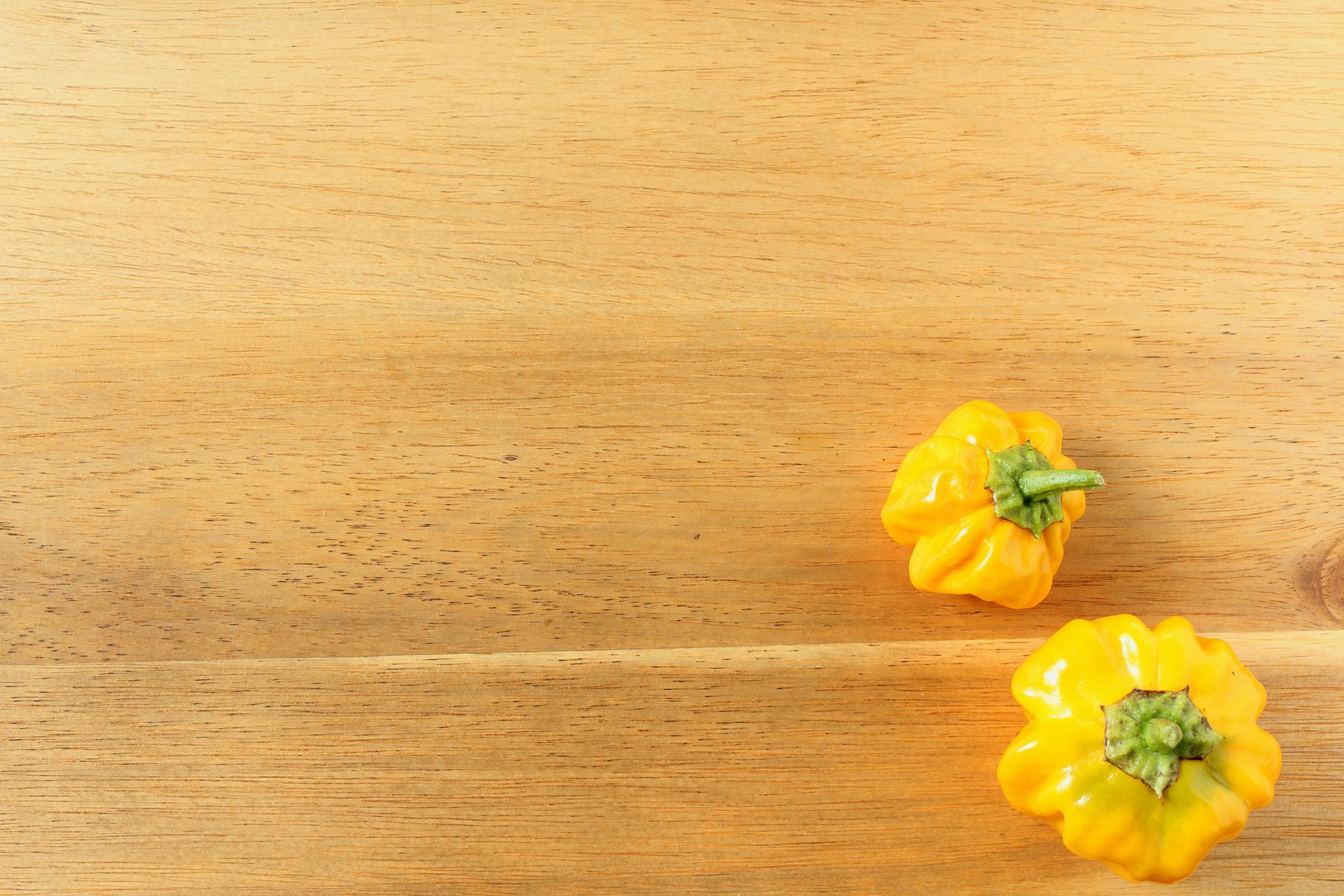 fresh yellow scotch bonnet chili peppers on a wooden board with copy space